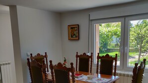 En matplats med ett träbord och stolar, ett element och ett fönster med utsikt över grönområden.