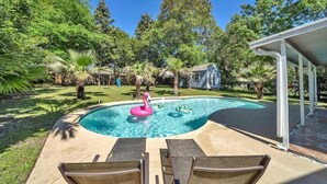 Um quintal com piscina, espreguiçadeiras e uma casa.