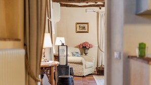 A cozy living room with a sofa, a vase of flowers, and a framed picture on the wall. - Dimora delle Camelie, a traditional stylish stone farmhouse with garden on the hills of Compitese between Lucca and Pisa (Pieve di Compito)