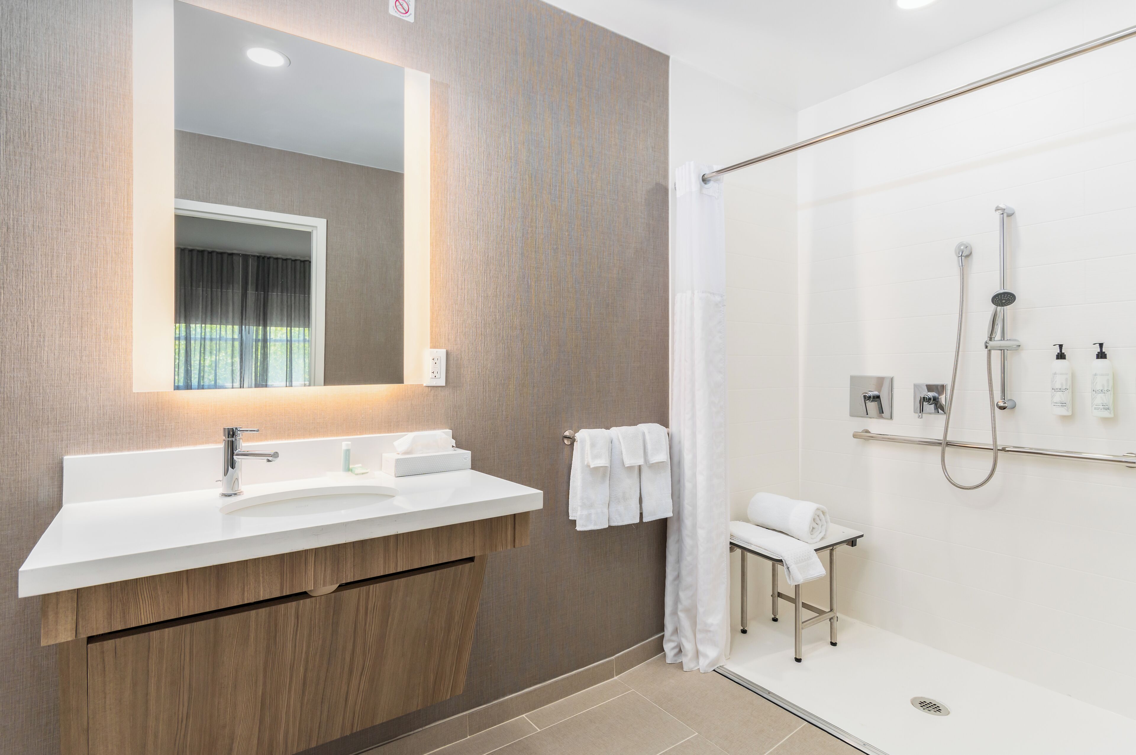 A modern bathroom with a large mirror, a white sink, and a shower area.