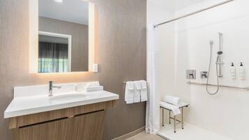 Un baño moderno con un espejo grande, un lavamanos blanco y una zona de ducha.