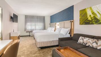 Una habitación de hotel con una cama grande, un sofá, un escritorio y un televisor.