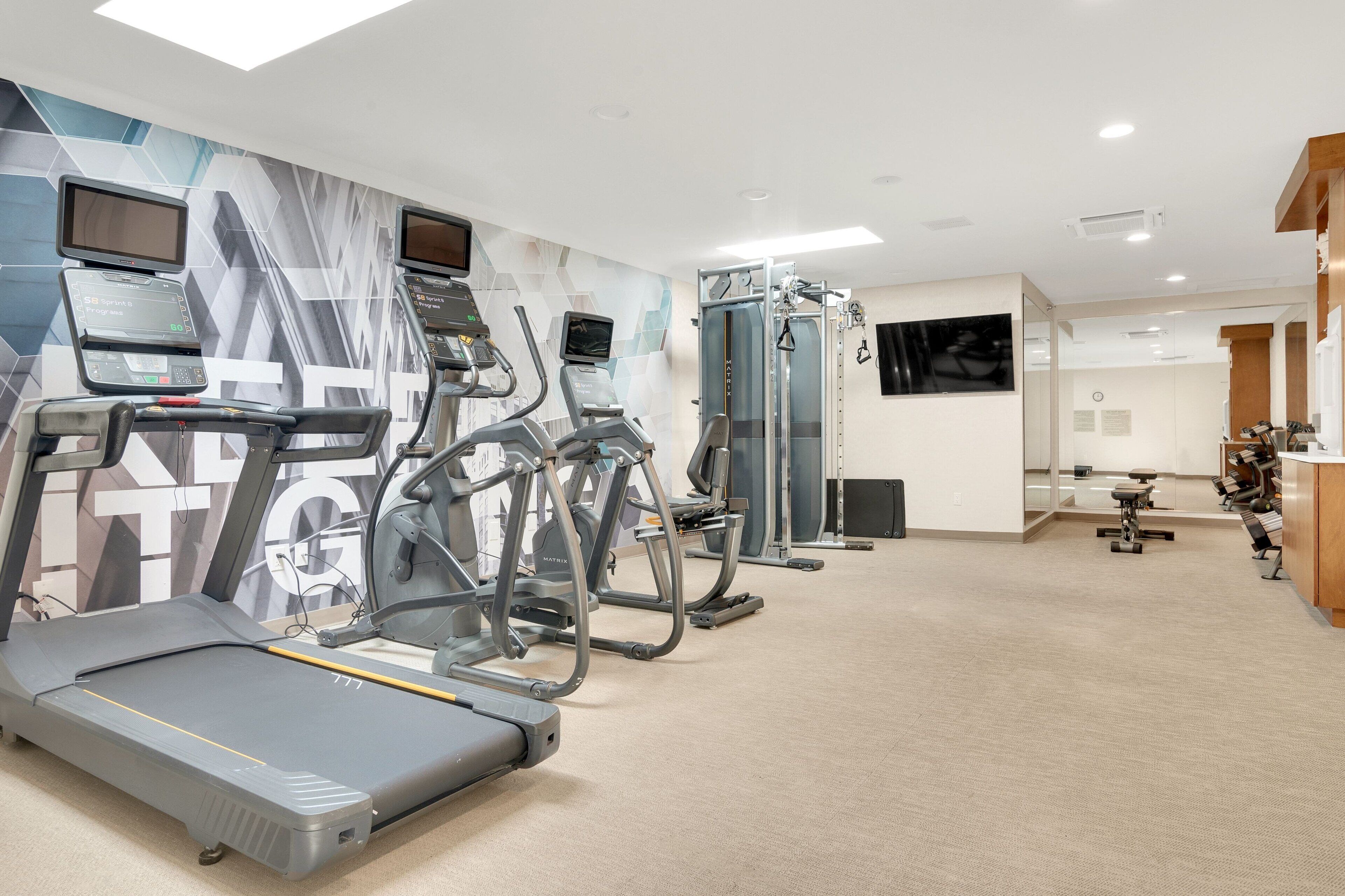 A gym with treadmills, elliptical machines, and a weight machine.