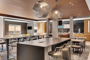 A modern hotel lobby with a central bar area, multiple seating arrangements, and large windows providing views of the outside. - SpringHill Suites by Marriott Freeport Brunswick (Freeport)