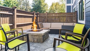 An outdoor patio with a fire pit, seating area, and chairs.