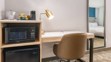 Habitación de hotel con microondas, cafetera y escritorio con silla.