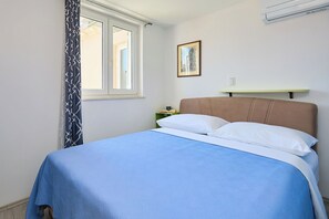 A bedroom with a bed, a window, a nightstand, and a wall-mounted shelf. - Joyful Place - Three Bedroom Apartment, Sleeps 6 (Dubrovnik)