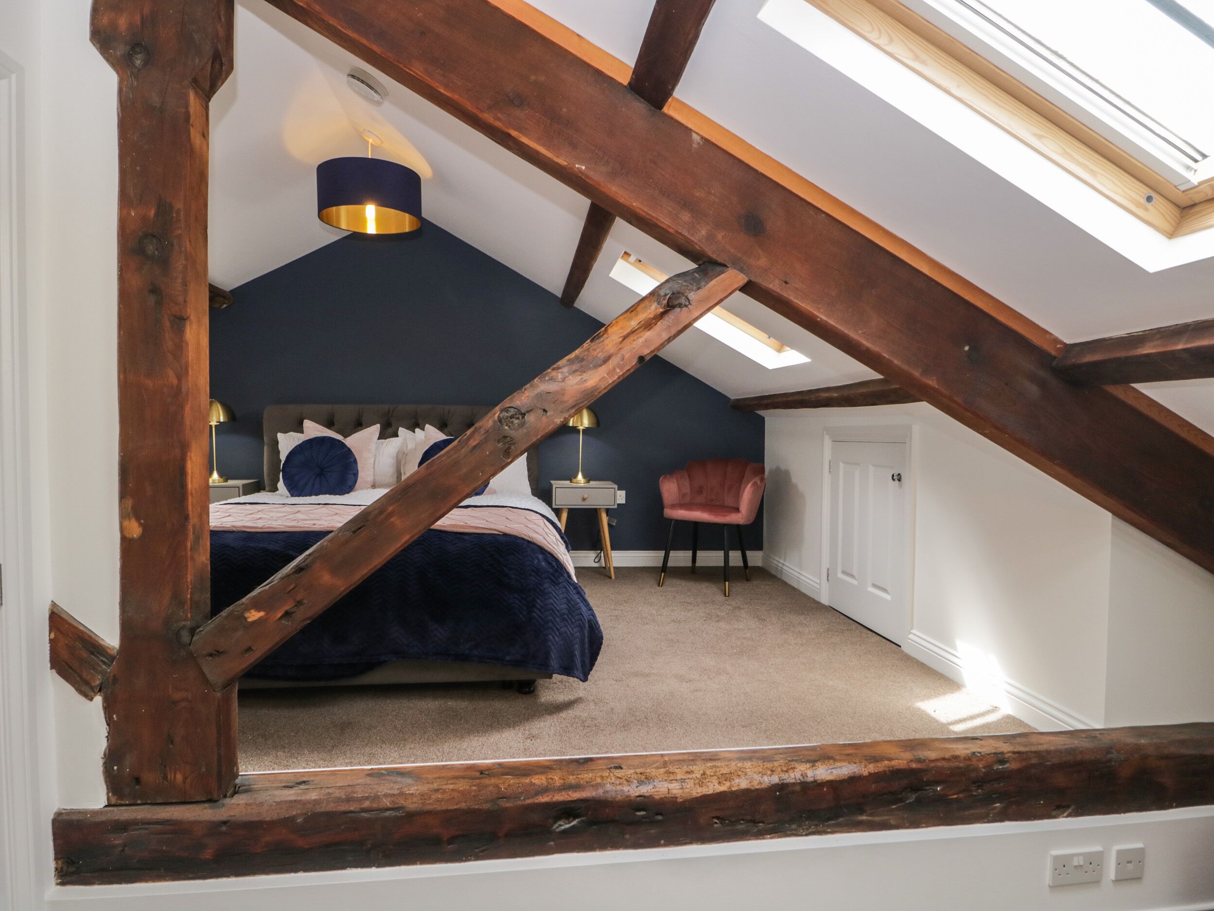 A bedroom with a sloped ceiling, a bed, a chair, and a small table.
