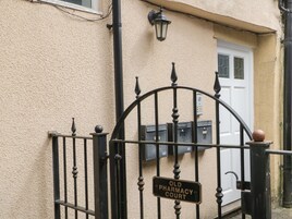 A wrought iron gate with a sign reading "Old Pharmacy Court."