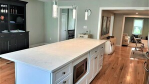 A spacious kitchen with a large island, wooden flooring, and pendant lighting. - Beautiful home!!! Private game room, swimming pool and pets allowed. (Sandwich)