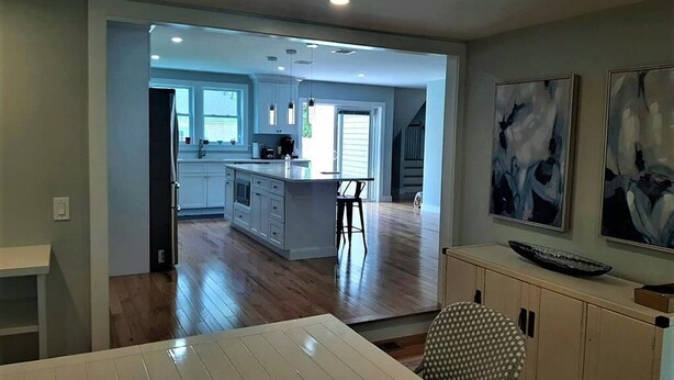A spacious kitchen with a central island, a dining area with a white table, and a view of the living area. - Beautiful home!!! Private game room, swimming pool and pets allowed. (Sandwich)