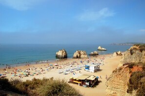 Una playa con grandes formaciones rocosas, una orilla arenosa y un pequeño edificio con un letrero.
