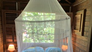 A bed with a canopy, a nightstand with a lamp, and wooden walls. - ecolodge Martinique (Fort-de-France)
