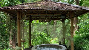 A hot tub under a wooden gazebo surrounded by lush greenery. - ecolodge Martinique (Fort-de-France)