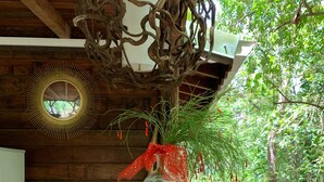 A wooden table with a glass vase containing a plant, a seashell, and a decorative piece. - ecolodge Martinique (Fort-de-France)