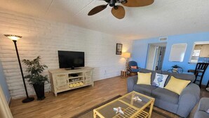 A living room with a television, sofa, coffee table, and a ceiling fan. - King 1bd/1ba Condo w/ Pool View & Beach Access (Port Aransas)