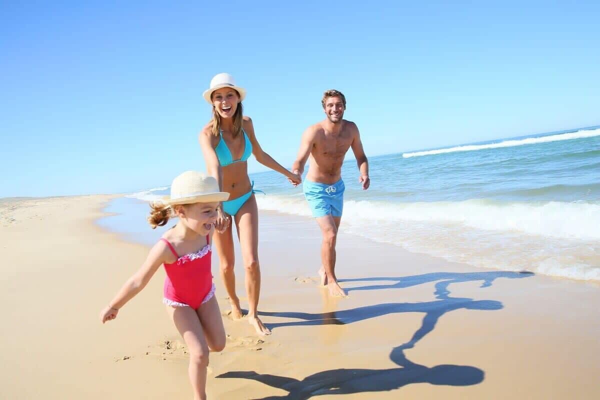 A beach scene with three people walking on the sand.