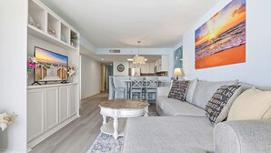 A living room with a sofa, a dining table, and a kitchen in the background. - Paradise Ocean View at Sand Dunes Resort (Myrtle Beach)
