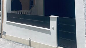 Un edificio moderno con un área exterior cubierta, un garaje y una escalera que conduce a un nivel superior.