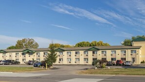 Ein mehrstöckiges Motel mit Innenhof, Parkplatz und einem Gebäude mit Gründach.