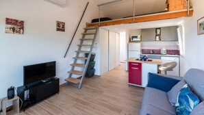 A compact living space with a loft bedroom, a kitchenette, a TV, and a sofa. - Ambroggio - Grand studio avec mezzanine - Vue Mer (Lumio)