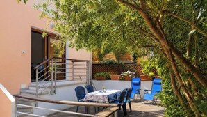 A patio with a table and chairs, a wooden deck, and a staircase leading to an upper level. - Libeccio | Relax Terrace 30m from the beach (Isola Rossa)