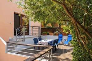 Eine Terrasse mit Tisch und Stühlen, ein Holzdeck und eine Treppe zu einer erhöhten Ebene.