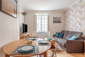 A modern living room with a dining area, a sofa, and a television.