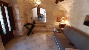 Un espacio de sala acogedor con pared de piedra, un sofá, un sillón y una lámpara.