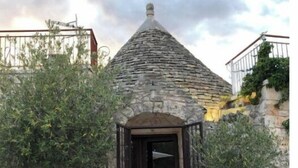 Un edificio de piedra con techo cónico y puerta central.