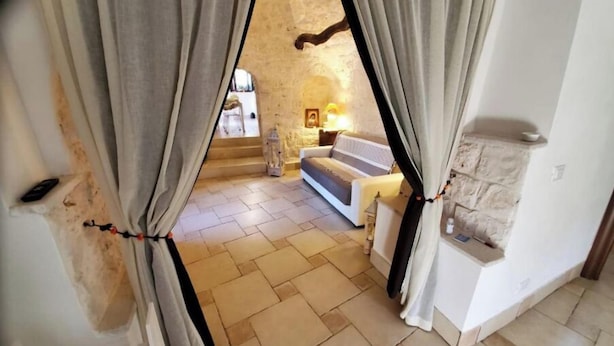 Una sala de estar acogedora con un sofá, una chimenea de piedra y vistas por un vano de puerta.