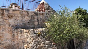 Un muro de piedra con una reja de metal y un pequeño árbol.