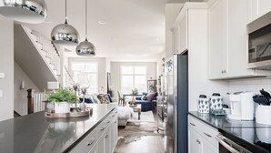 Een moderne keuken met een centraal eiland, roestvrijstalen apparatuur en hanglampen.
