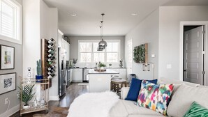 Een moderne keuken met witte kasten, een centraal eiland en een eethoek met barstoelen.