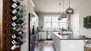 Een moderne keuken met een wijnrek, roestvrijstalen apparatuur en hanglampen.