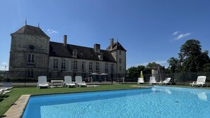 A swimming pool with lounge chairs and a large building in the background.