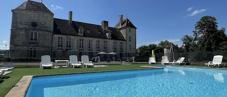 Una piscina con sillas de descanso y un edificio grande al fondo.