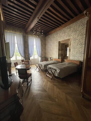 Cozy retreat with a traditional design, featuring a herringbone-patterned floor, sloped ceiling, and a comfortable bed with bedside tables and lamps.
