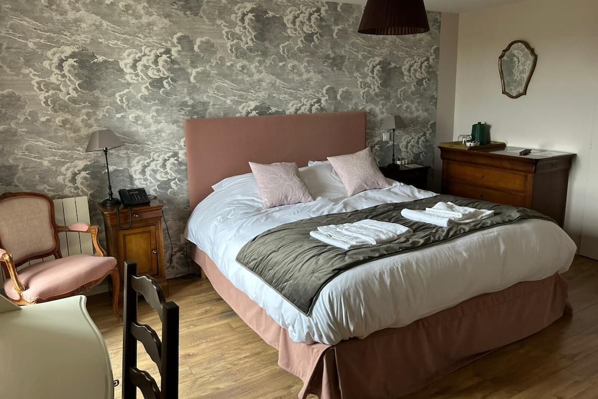 A bedroom with a bed, a chair, a nightstand, a lamp, and a dresser.