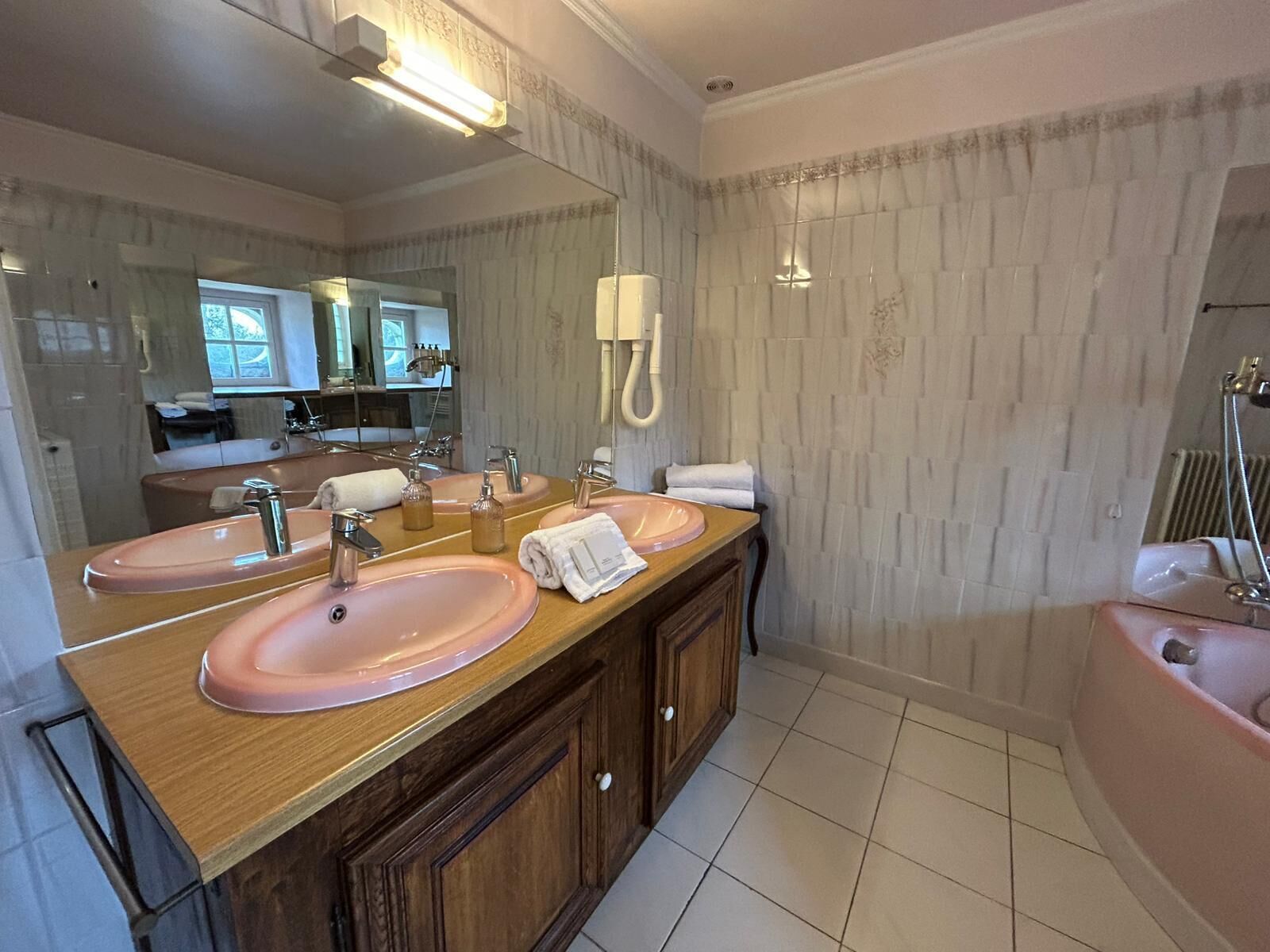 A bathroom with two sinks, a mirror, a vanity, a bathtub, and a shower.