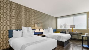 Ein Hotelzimmer mit zwei Betten, einem Schreibtisch, einem Stuhl und einem Fenster mit Blick.