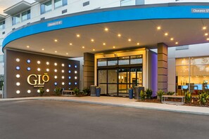 A hotel entrance with a blue awning, illuminated signage, and a clear entrance. - Glō Best Western Pooler - Savannah Airport Hotel (Savannah)