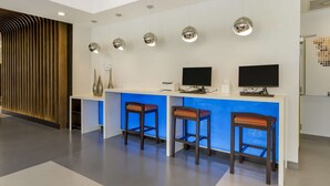 Ein Empfangsbereich im modernen Design mit einer Rezeption, zwei Barhocker, einem Flachbildfernseher und Pendelleuchten.