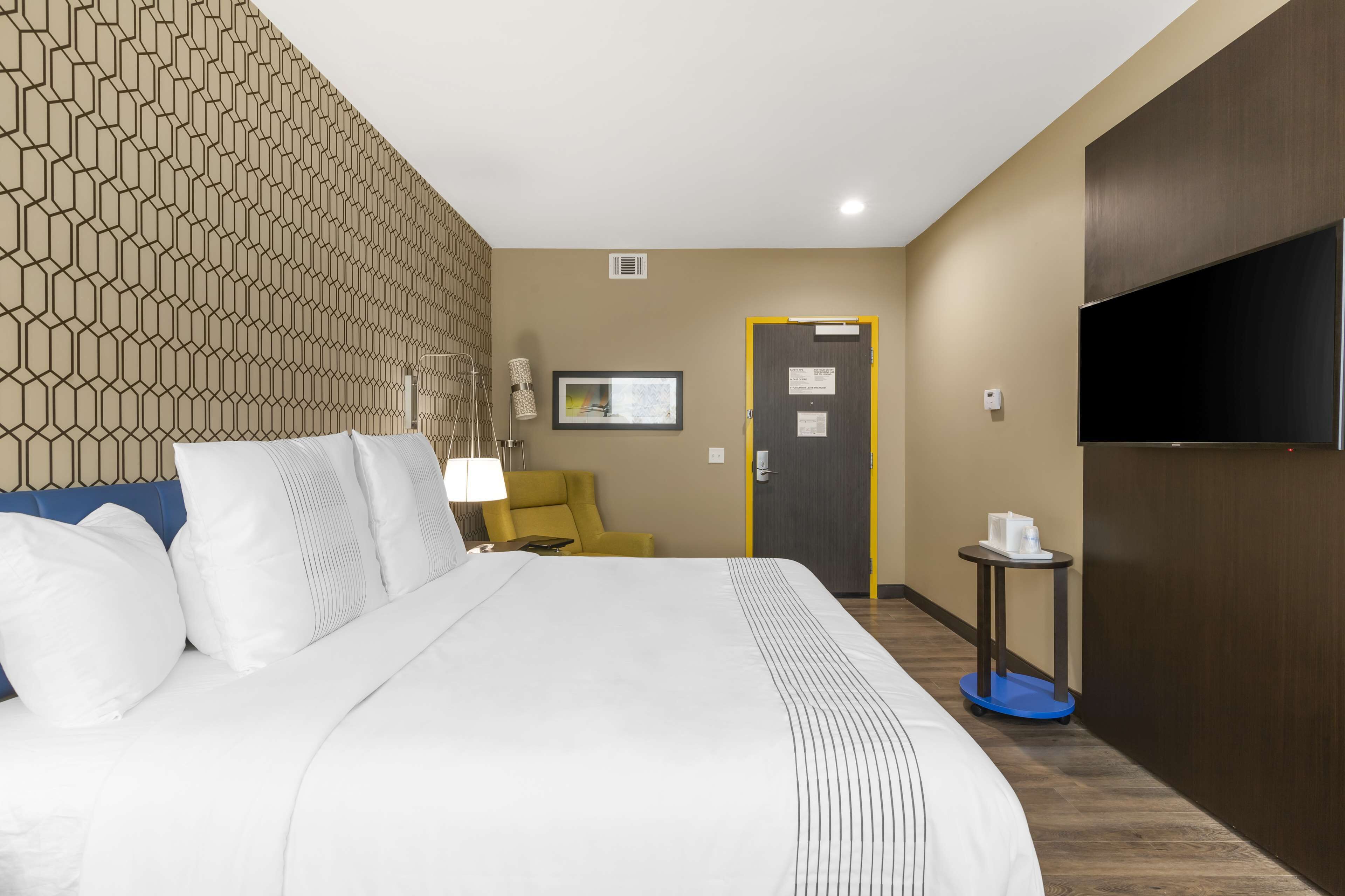 A hotel room with a large bed, a television, a desk, and a chair.