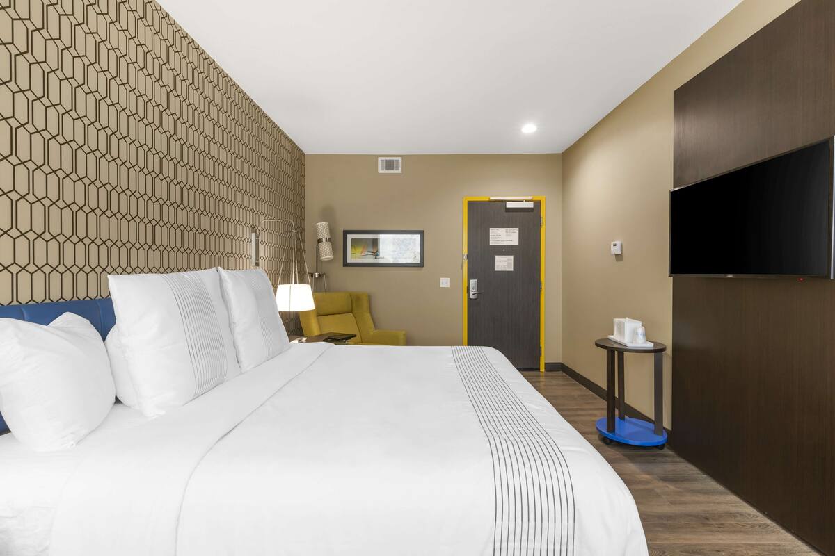 Une chambre d’hôtel avec un grand lit, une télévision, un bureau et une chaise.