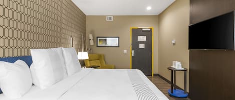 A hotel room with a large bed, a television, a desk, and a chair.