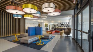 Eine moderne Lobby mit einem blauen Sofa, gelben Tischen und farbenfrohen Pendelleuchten.