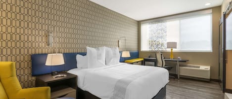 A hotel room with a bed, a desk, a chair, and a window with a view.