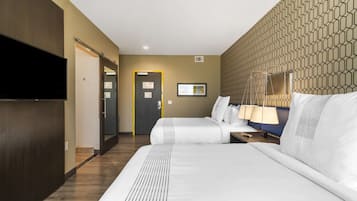 Habitación de hotel con una cama grande, televisión, escritorio con lámpara y pared con diseño.