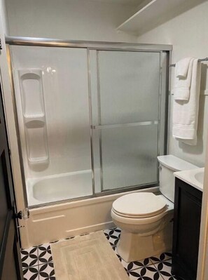 Bathroom features a glass-enclosed shower stall, toilet, and sink area.